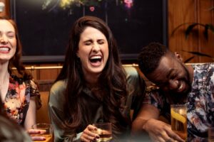 Friends Holding Drinks in a Bar and Laughing