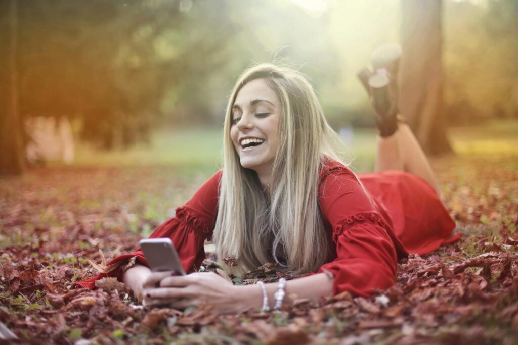 Woman in Red Dress Lying on Brown Dried Leaves