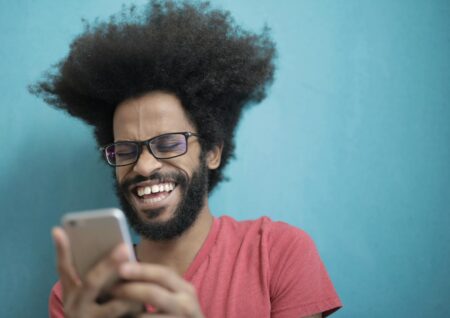 Man in Red Crew Neck Shirt Wearing Black Framed Eyeglasses Holding Silver Iphone 6