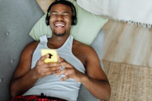 A Man in Tank Top Lying on the Couch with Headphones