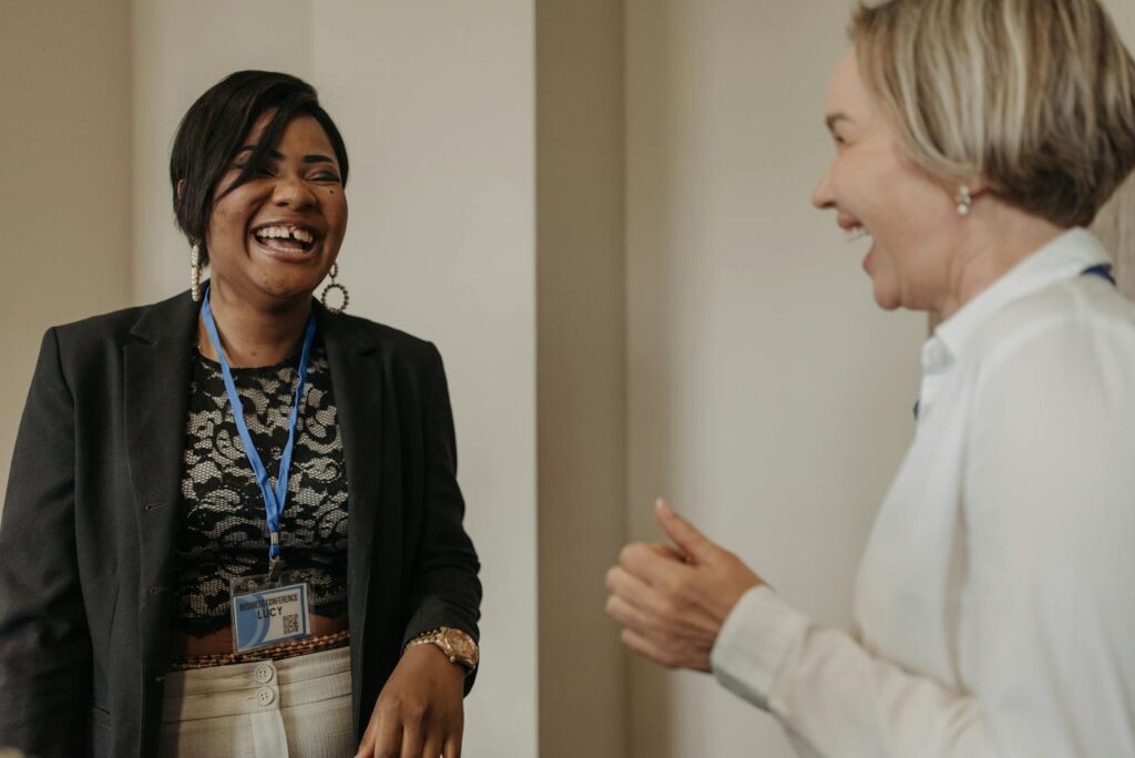 Two Women Wearing Long Sleeves Laughing Together in a Room